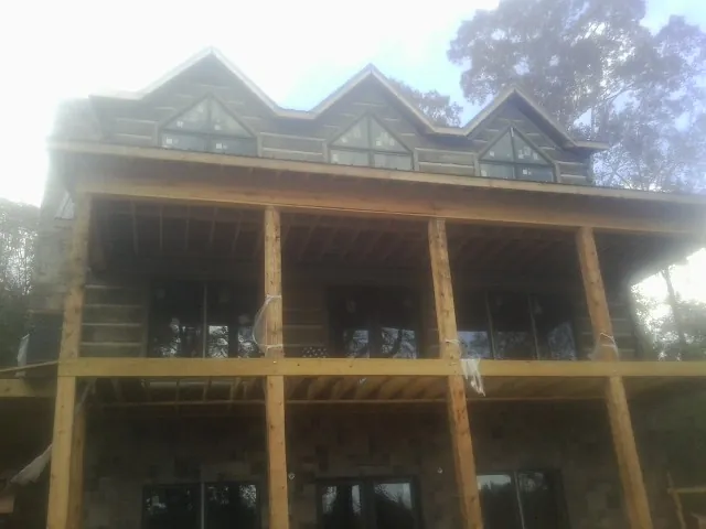Dormers and porch framing on a large log home under construction — Roof Coating work by our crew in Jacksonville